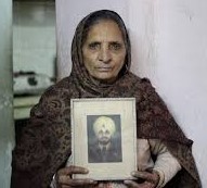 A Sikh widow holds the photo of her deceased husband.